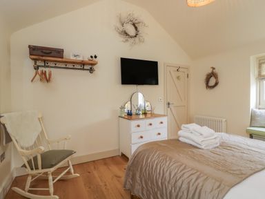 A bedroom with a rocking chair and a television at The Little Loft in Burford
