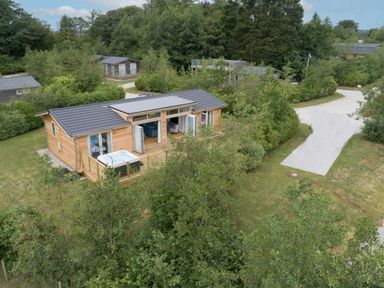 A wooden house with opened doors and a hot tub on the deck surrounded by trees at 5 Southern Place in Dobwalls