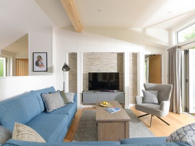 A living room with a blue sofa a wooden coffee table and a gray armchair at 5 Southern Place in Dobwalls
