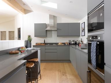 A kitchen with grey cabinets a countertop with bread stools and built in appliances at 5 Southern Place in Dobwalls