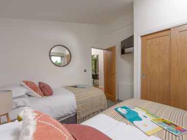 A bedroom with two single beds a round wall mirror and wooden closet doors at 5 Southern Place in Dobwalls
