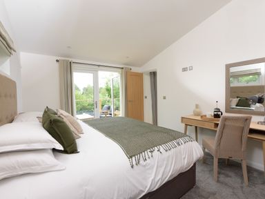 A bedroom with a bed green throw pillows and a desk with a chair and mirror at 5 Southern Place in Dobwalls