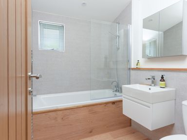 A bathroom with a bathtub and shower next to a sink and mirror cabinet at 5 Southern Place in Dobwalls