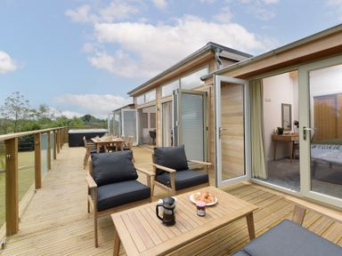 A wooden deck with outdoor seating and dining area next to a house with open glass doors at 5 Southern Place in Dobwalls