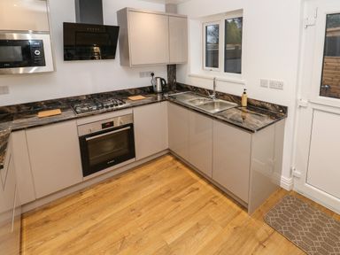 A kitchen with a gas stove oven microwave sink and wooden floor at Swn Y Mor in Burry Port