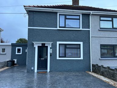 The exterior of a two-story semi detached house with a driveway and dark door at Swn Y Mor in Burry Port