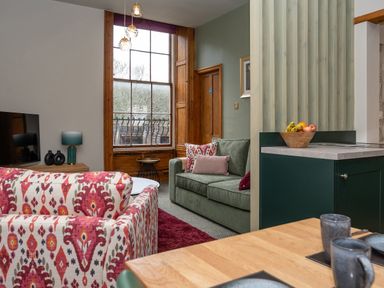 A living room with patterned armchairs a green sofa and a wooden dining table at Watermouth Castle Bassett Apartment Berrynarbor near Ilfracombe