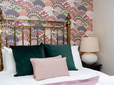A bed with green and pink pillows and a lamp on a bedside table at Watermouth Castle Bassett Apartment in Berrynarbor near Ilfracombe
