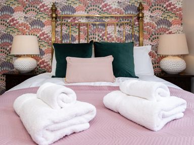 A bed with rolled white towels pillows and lamps on bedside tables at Watermouth Castle Bassett Apartment Berrynarbor near Ilfracombe