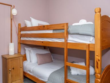A bedroom with a wooden bunk bed and a wooden bedside table with a lamp at Watermouth Castle Bassett Apartment Berrynarbor near Ilfracombe
