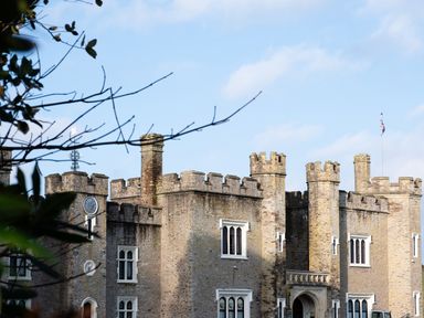 A stone castle with battlements towers and windows under a blue sky at Watermouth Castle Bassett Apartment in Berrynarbor near Ilfracombe