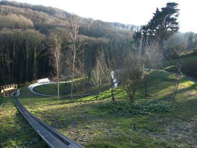 An outdoor bobsled track running through a grassy wooded hillside
