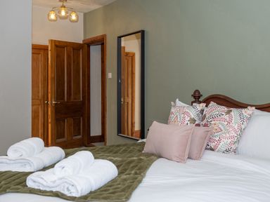 A bedroom with a bed and rolled towels on a green blanket at Watermouth Castle Rhododendron Apartment in Berrynarbor near Ilfracombe