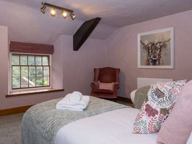 A bedroom with a bed towels on top and armchair by a window at Watermouth Castle Rhododendron Apartment Berrynarbor near Ilfracombe