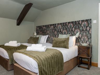 A bedroom with two single beds side by side with green bedding and patterned headboard at Watermouth Castle Rhododendron Apartment Berrynarbor near Ilfracombe