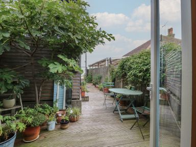 A garden with wooden decking and potted plants at The Artist's Cabin By The Sea Herne Bay