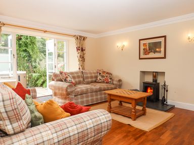 A living room with plaid sofas cushions wooden coffee table and a wood burning stove at Culver Court Cottage Venny Tedburn near Crediton