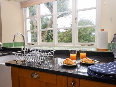 A kitchen countertop with two croissants and glasses of orange juice near a window at Culver Court Cottage in Venny Tedburn near Crediton