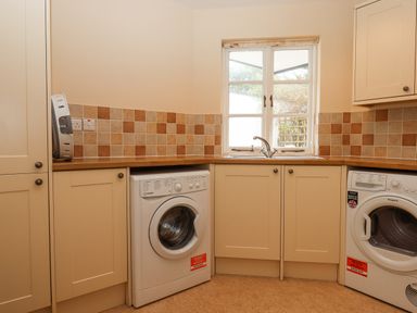 A laundry room with a washing machine dryer sink and cabinets at Culver Court Cottage in Venny Tedburn near Crediton