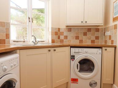 A utility room with a washing machine dryer sink and tiled walls at Culver Court Cottage Venny Tedburn near Crediton