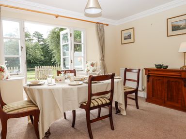 A dining room with a table set for meals and wooden chairs at Culver Court Cottage in Venny Tedburn near Crediton