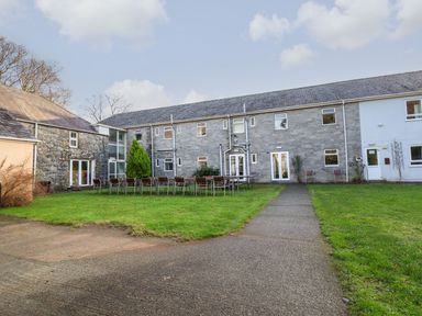 An outdoor courtyard with tables and chairs in front of a two-story stone and white building at The Bevan in Bontnewydd Gwynedd