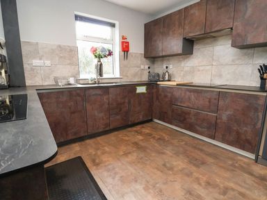 A kitchen with brown cabinets a window above a sink countertop appliances and knives at The Bevan in Bontnewydd Gwynedd