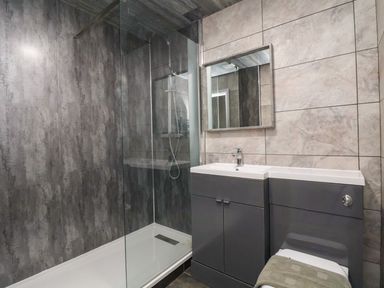 A bathroom with a walk-in shower next to a sink and cabinet unit with a mirror above at The Bevan in Bontnewydd Gwynedd
