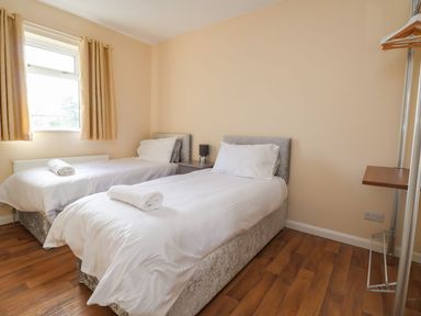 A bedroom with two single beds and a window with curtains at The Bevan in Bontnewydd Gwynedd