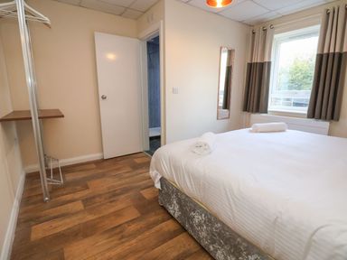 A bedroom with a double bed and rolled towels near a window with curtains at The Bevan in Bontnewydd Gwynedd