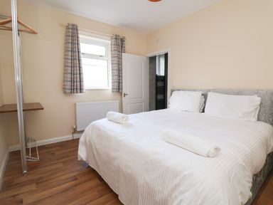 A bedroom with a double bed curtain window and an open door at The Bevan in Bontnewydd Gwynedd
