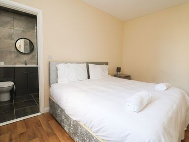 A bedroom with a bed with white linens two towels on the bed a nightstand with a lamp and an ensuite bathroom at The Bevan in Bontnewydd Gwynedd