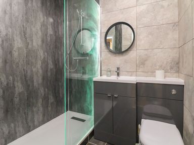 A bathroom with a walk in shower sink toilet and round mirror at The Bevan in Bontnewydd Gwynedd