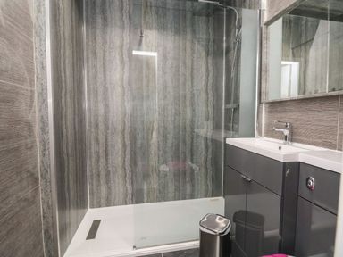 A bathroom with a walk-in shower glass door vanity sink and trash can at The Bevan in Bontnewydd Gwynedd