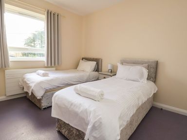 A bedroom with two single beds a window with curtains and a nightstand with a lamp at The Bevan in Bontnewydd Gwynedd