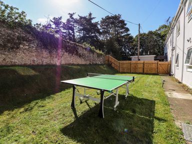A table tennis table on a grass backyard next to a white building at The Bevan in Bontnewydd Gwynedd