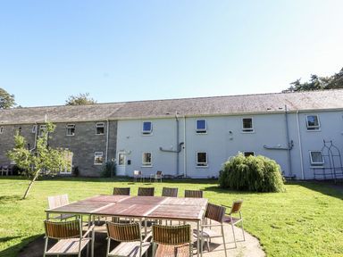 Outdoor dining tables and chairs on a lawn in front of a two story building at The Bevan in Bontnewydd Gwynedd