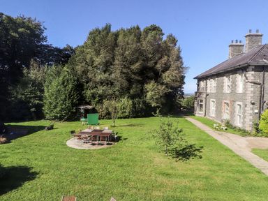 A green lawn with chairs and a table near a stone building at The Bevan in Bontnewydd Gwynedd