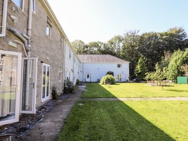 A grassy garden area with outdoor seating beside a two story building at The Bevan in Bontnewydd Gwynedd