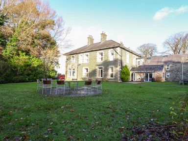A lawn with outdoor chairs and tables in front of a large stone building at The Bevan in Bontnewydd Gwynedd