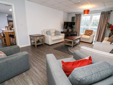 A living room with armchairs a sofa a coffee table a side table and a television at Cadwaladr in Bontnewydd near Caernarfon