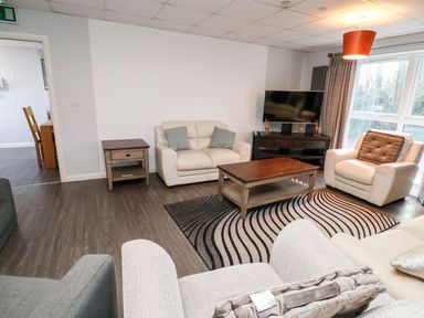 A living room with armchairs sofa coffee table and television at Cadwaladr in Bontnewydd near Caernarfon