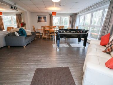 A living room with sofas a foosball table and a dining table with chairs at Cadwaladr in Bontnewydd near Caernarfon