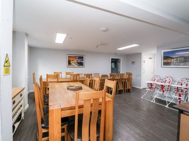 A dining room with wooden tables and chairs and three high chairs with polka dot seats at Cadwaladr in Bontnewydd near Caernarfon