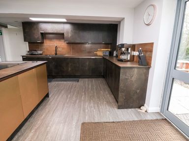 A kitchen with dark cabinets countertop appliances and a door leading outside at Cadwaladr in Bontnewydd near Caernarfon