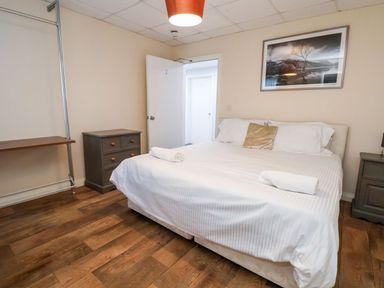 A bedroom with a double bed two bedside tables wooden floor and a framed picture on the wall at Cadwaladr in Bontnewydd near Caernarfon