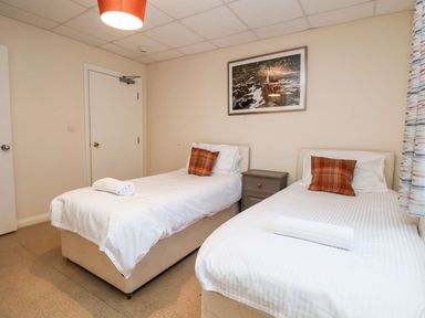 A bedroom with two single beds white bedding a nightstand between beds and a framed picture on the wall at Cadwaladr in Bontnewydd near Caernarfon