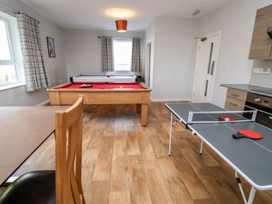 A game room with a pool table air hockey table and table tennis table at Cadwaladr in Bontnewydd near Caernarfon