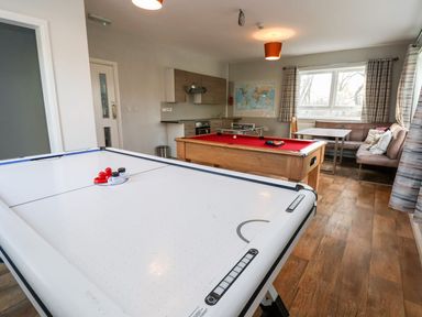 A game room with an air hockey table a pool table a kitchenette and a seating area at Cadwaladr in Bontnewydd near Caernarfon