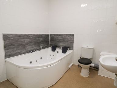 A bathroom with a jacuzzi tub toilet and sink at Cadwaladr in Bontnewydd near Caernarfon